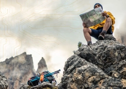 Hiker on a rocky mountaintop reads a map while a backpack lies nearby, with a circuit-pattern overlay in the sky for tech theme.
